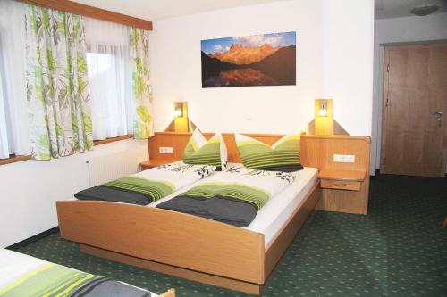 ein Schlafzimmer mit einem großen Bett mit grünen und gelben Kissen in der Unterkunft Appartements Platzis in Schruns-Tschagguns