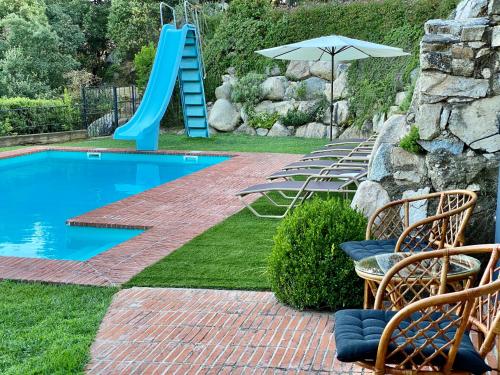 una piscina con scivolo, sedie e ombrellone di Casa Rural Can Mananna Lloguer íntegre a Sant Feliu de Buixalleu
