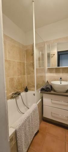 a bathroom with a bath tub and a sink at Charmant T2 climatisé avec belle vue , Golf de Pont-Royal in Mallemort