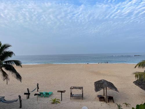 a beach with chairs and an umbrella and the ocean at Sea Crest Beach Villa in Ambalangoda