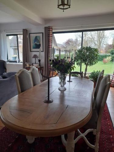 une table en bois avec des chaises et un vase de fleurs dessus dans l'établissement La Closerie gîte de charme près de Giverny, à Hardencourt-Cocherel