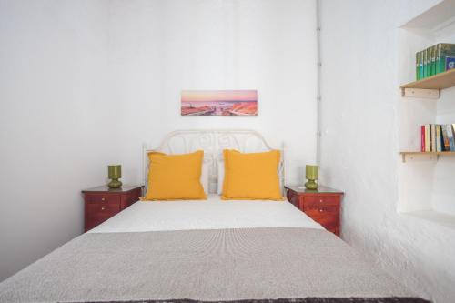 a bedroom with a bed with two yellow pillows at Agaete Botanic - Rooftop Solarium in Agaete