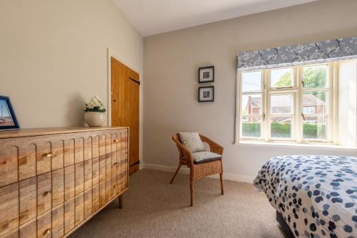 ein Schlafzimmer mit einem Bett und einem Stuhl und einem Fenster in der Unterkunft Peony Cottage in Helhoughton
