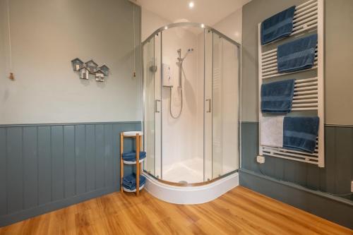 eine Dusche in einem Badezimmer mit blauen Wänden und Holzböden in der Unterkunft Peony Cottage in Helhoughton