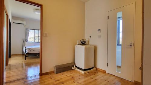 a room with a refridgerator next to a door at プール バーベキュー場付き 貸し切り別荘 in Sano