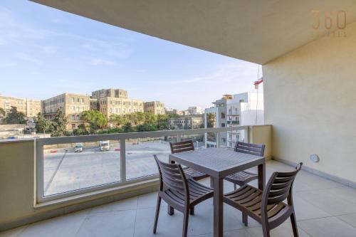a balcony with a table and chairs and a large window at Lovely designer 3BR Apt with Private Terrace with BBQ by 360 Estates in Tal-Pietà