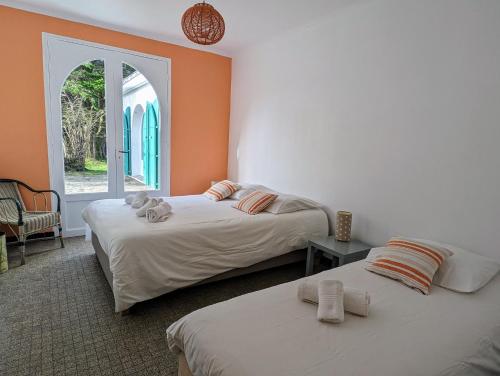 deux lits dans une chambre avec une fenêtre ouverte dans l'établissement Longère familiale proche mer et golf, à Pornic