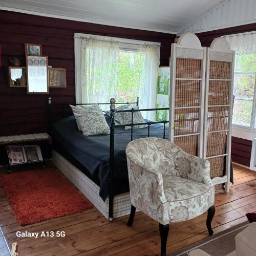 a bedroom with a bed and a chair at Cottage / Mökki, unique summer cottage in Vihti