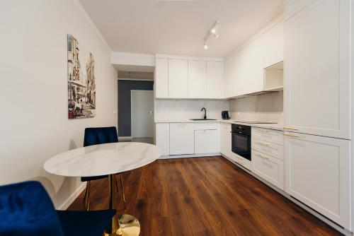 a kitchen with white cabinets and a white table at 3 Bedrooms Premium Bella Blue for 8 Guests with AC and Free out side Parking in Rzeszów