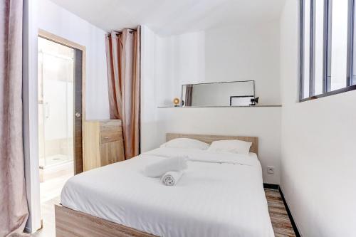 a white bedroom with a bed and a window at Le Cozy - Saint Cyr in Saint-Cyr-lʼÉcole