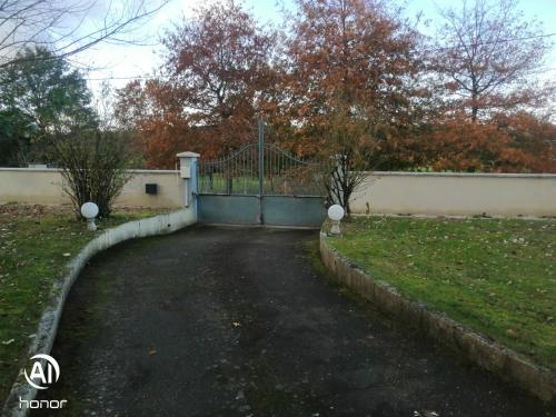 une allée avec un portail dans une cour dans l'établissement chambres d hôtes Coco, à Arnage