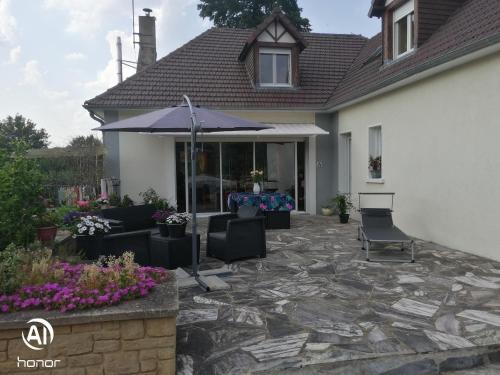 une terrasse avec un parasol en face d'une maison dans l'établissement chambres d hôtes Coco, à Arnage