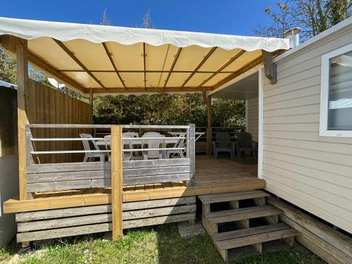 une terrasse en bois avec un auvent sur le côté d'une maison dans l'établissement Camping Le Repos, à Saint-Palais-sur-Mer