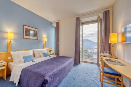 a hotel room with a bed and a desk and a window at Hôtel Bon Rivage in Vevey