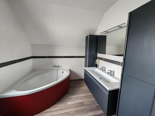 La salle de bains est pourvue d'une grande baignoire et d'un lavabo. dans l'établissement Maison spacieuse, à Moyon