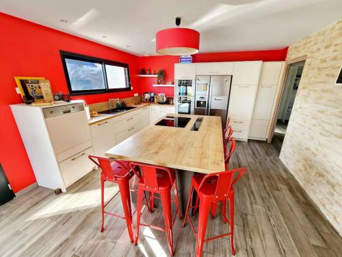 une cuisine avec des murs rouges et une table en bois et des chaises rouges dans l'établissement Maison spacieuse, à Moyon