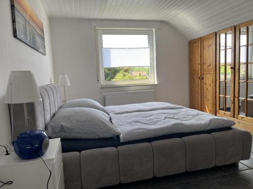 a bedroom with a large bed with a window at NEU! Ferienwohnung Up de Warf in Dornum