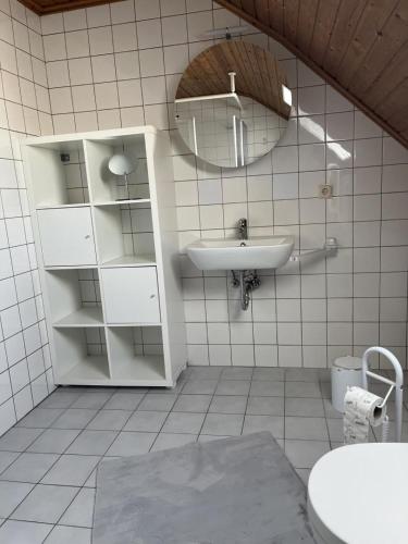 a white bathroom with a sink and a mirror at NEU! Ferienwohnung Up de Warf in Dornum
