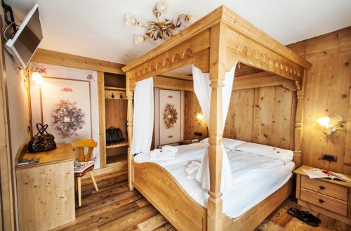 a bedroom with a canopy bed in a wooden room at Hotel Arnika Wellness in Passo San Pellegrino