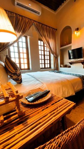 a bedroom with a bed with a remote control on a table at Al Koot Heritage Hotel in Al Hofuf