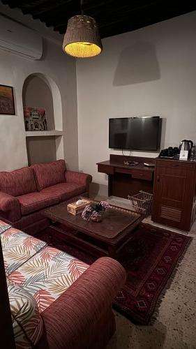 a living room with red couches and a tv at Al Koot Heritage Hotel in Al Hofuf