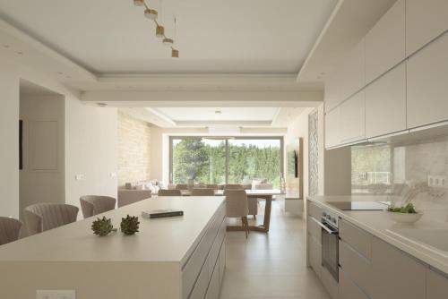 cocina con armarios blancos y comedor en Reflection Villa, Heated Pool & Absolute Seclusion, By ThinkVilla, en La Canea