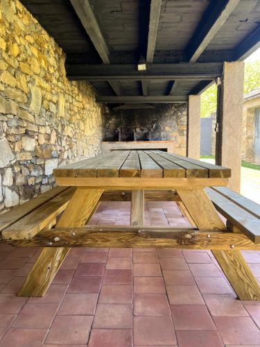 einem Picknicktisch aus Holz vor einer Steinmauer in der Unterkunft Can Sau in Sant Joan de les Abadesses