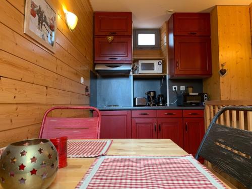 una cocina con armarios rojos y una mesa de madera con sidra de mesa en Studio Tiny en duplex - face télécabines, en Ax-les-Thermes