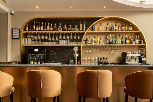 a bar with brown chairs and a shelf with alcohol at Mercure Angoulême Hôtel de France in Angoulême