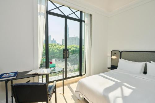 a bedroom with a bed and a desk and a window at Opartment - People's Square 远东饭店 - 人民广场 in Shanghai