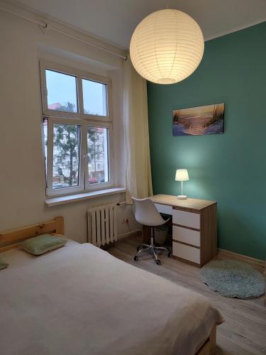 a bedroom with a bed and a desk and a lamp at Magnolia rooms in Toruń
