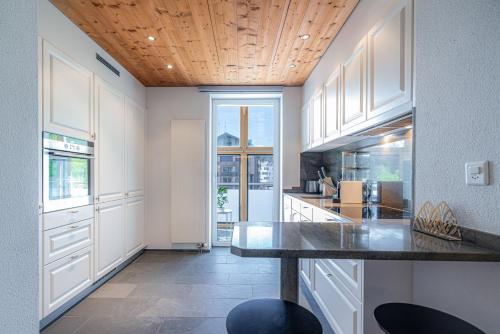 a kitchen with white cabinets and a wooden ceiling at VISIMO Apartments Flims with private Sauna in Flims