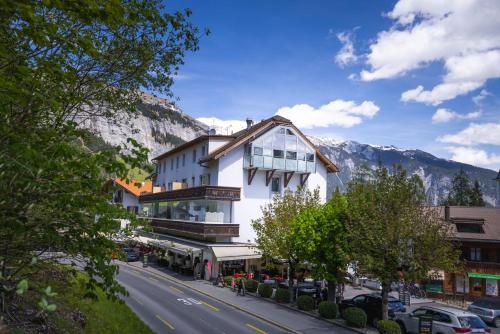 a white building on a street with mountains in the background at VISIMO Apartments Flims with private Sauna in Flims