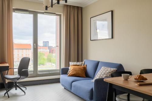 un soggiorno con un divano blu davanti a una finestra di Flatbook - City Center SPA Apartments Grano Residence with Parking a Danzica