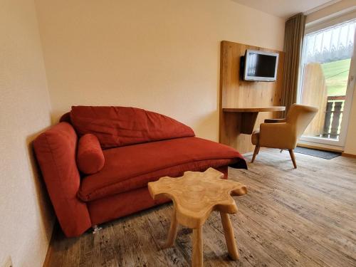 a living room with a red couch and a chair at Gasthaus Pension Donishäusle in Titisee-Neustadt