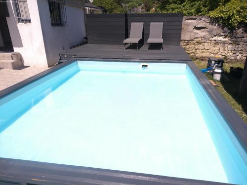 a large swimming pool with two chairs in a yard at A 2 pas d AZAY in Neuil