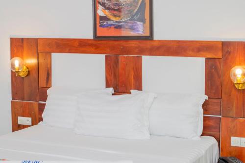 Bett mit einem Kopfteil aus Holz mit einem Bild darüber in der Unterkunft Hotel BKBG Benin in Cotonou