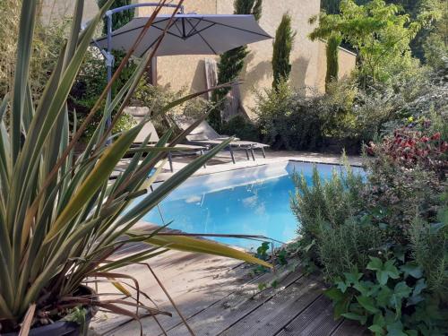 - une piscine dans un jardin avec une table et un parasol dans l'établissement L' Intimiste : avec Piscine privée et Jacuzzi privé, à Fontaines-Saint-Martin