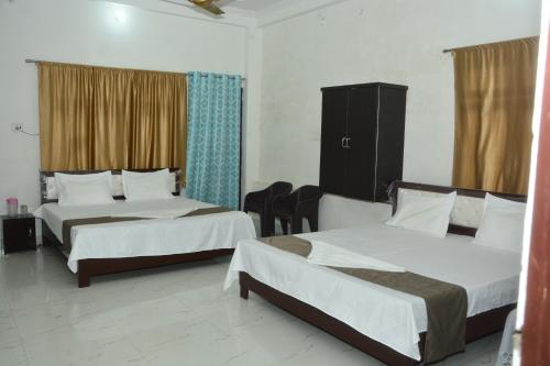 Habitación de hotel con 2 camas y 2 sillas en Hotel Chandrasha Villa, en Ayodhya
