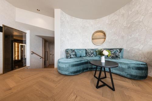a living room with a blue couch and a table at DAS GERSTL Alpine Retreat in Malles Venosta