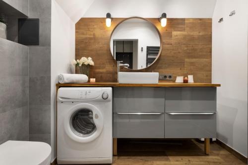 a bathroom with a washing machine and a mirror at Elite Apartments City Center Cosy Attic in Gdańsk