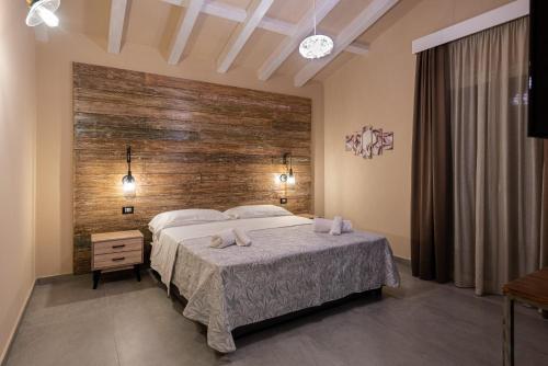 a bedroom with a bed and a wooden wall at Corten Hotel in Santa Maria di Licodia