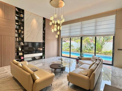 a living room with a couch and chairs and a tv at Looma Private Pool Villas in Pantai Cenang