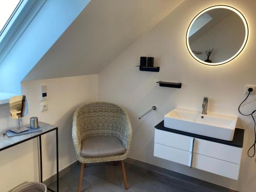 ein Badezimmer mit einem Waschbecken, einem Stuhl und einem Spiegel in der Unterkunft Gästehaus Bargteheide in Bargteheide