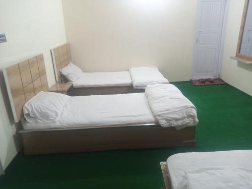 two beds in a room with a green floor at Hunza Cherry Guest House in Hunza