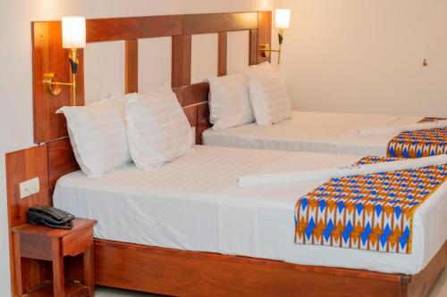 2 camas en una habitación de hotel con un teléfono en una mesa en Hotel BKBG Benin, en Cotonou