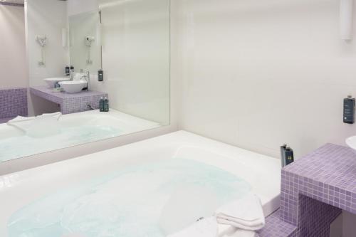 a bathroom with a tub and a sink and a mirror at Ariha Hotel Cosenza in Cosenza