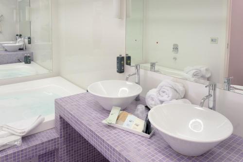 a bathroom with two sinks and a mirror at Ariha Hotel Cosenza in Cosenza