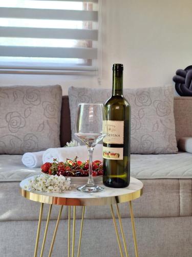 una botella de vino y una copa de vino en una mesa en Kućica na Drini "JAZ", en Višegrad