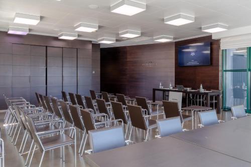 a conference room with tables and chairs and a screen at Ariha Hotel Cosenza in Cosenza